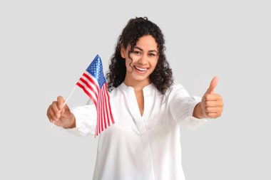 Güzel, mutlu, Afro-Amerikan bayrağı olan bir kadın beyaz arka planda baş parmak hareketi gösteriyor.