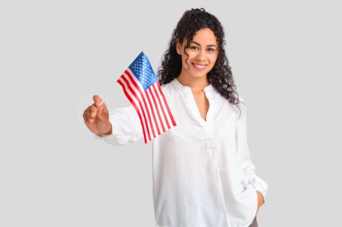 Beyaz arka planda Amerikan bayrağı olan güzel, mutlu, Afro-Amerikan bir kadın.