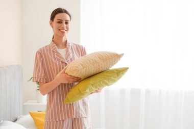 Young woman in pajamas with pillows in bedroom clipart