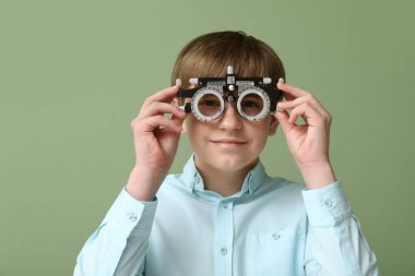 Yeşil arka planda optik deneme çerçevesinde küçük bir çocuk