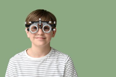 Yeşil arka planda optik deneme çerçevesinde küçük bir çocuk