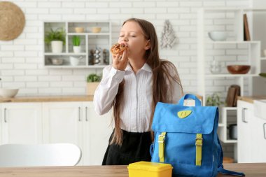 Sırt çantası, beslenme çantası ve evde fındık tartı olan küçük tatlı bir kız öğrenci.