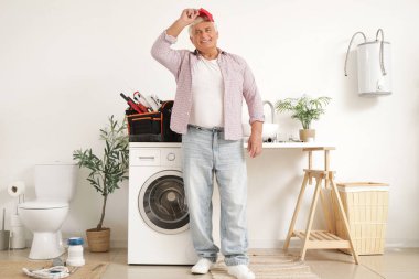 Banyosunda alet çantası olan yetişkin bir tesisatçı.