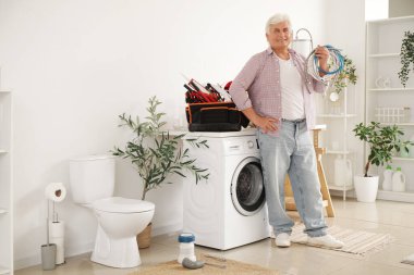 Banyosunda alet çantası olan yetişkin bir tesisatçı.