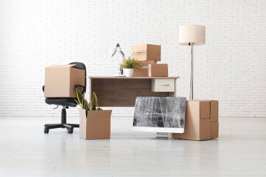 Taşınırken kutularla dolu bir masa, paket bilgisayar monitörü ve sandalye.