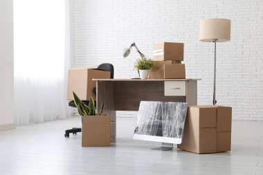 Taşınırken kutularla dolu bir masa, paket bilgisayar monitörü ve sandalye.