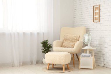 Oturma odasındaki çekmecelerin raflarında modern elektrikli vantilatörler var.