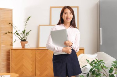 Evde dizüstü bilgisayarı olan Asyalı genç bir iş kadını.