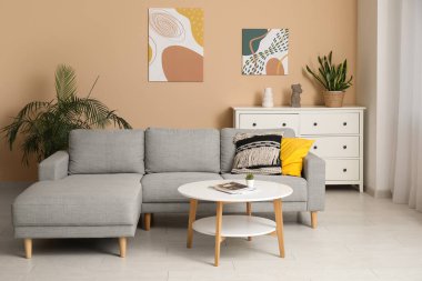 Rahat bir kanepe, kahve masası ve oturma odasındaki bej duvarda asılı bir resim.