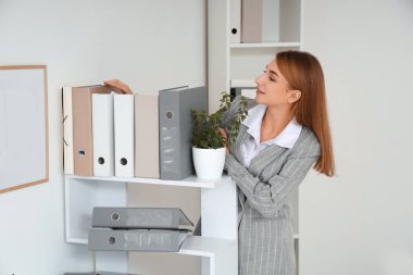 İş kadını ofisteki raftan belge klasörünü alıyor