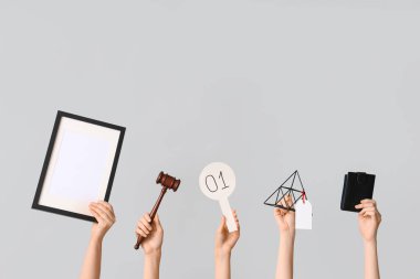 Açık artırma raketi, tokmak, cüzdan ve arka planda antika eşyaları olan kadın eller.