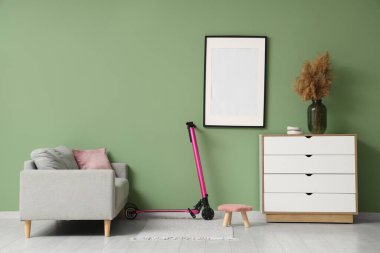 Oturma odasının içinde elektrikli scooter, kanepe ve boş çerçeve.