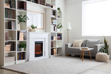 Kitaplıkları, kanepesi, sehpası ve şöminesi olan modern ev kütüphanesi.