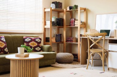 Konforlu kanepe, masa, işyeri ve kitaplıklar odanın içinde.