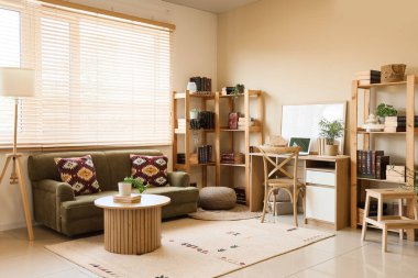 Konforlu kanepe, masa, işyeri ve kitaplıklar odanın içinde.