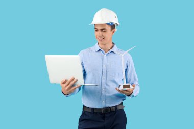 Mavi arka planda rüzgar türbini modeli ve dizüstü bilgisayarı olan erkek mühendis.