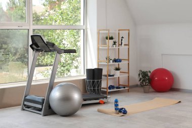 Raf ünitesi, koşu bandı ve spor ekipmanlarıyla hafif spor salonu.