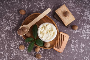 Bir kavanoz Shea yağı, fındık, saç tarağı ve sabun içeren kompozisyon grunge renk arkaplanı