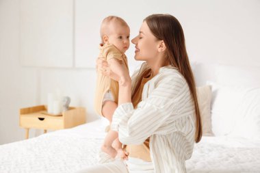 Mutlu anne ve küçük bebeği yatak odasında.