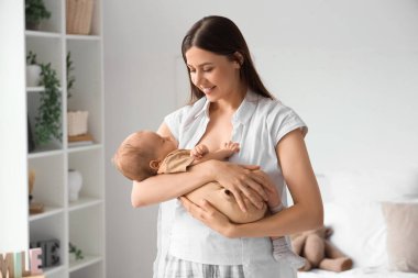 Mutlu anne küçük bebeğini yatak odasında tutuyor.