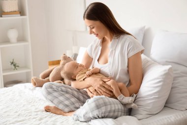 Mutlu anne ve bebeği yatak odasında oturuyor.