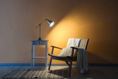 Masada parlayan lamba ve karanlık odada koltuk.