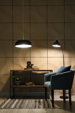 Geceleri koltuğu, raf ünitesi ve parlayan lambaları olan karanlık oturma odasının içinde.