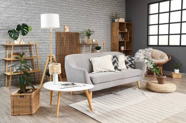 Kanepesi, raf ünitesi ve bitkileri olan modern oturma odasının içinde.