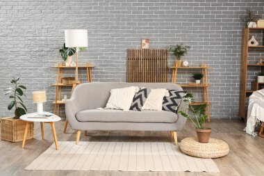 Kanepesi, raf ünitesi ve bitkileri olan modern oturma odasının içinde.