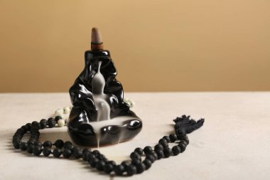 Tütsü tutucu, yanan koni ve dua boncuklarıyla aydınlık masada