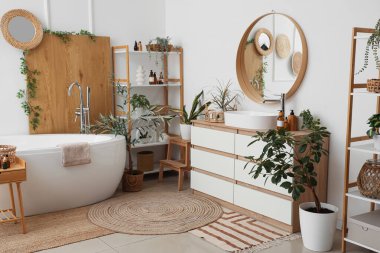 Çekmeceleri, küveti, saksısı ve raf ünitesi olan güzel bir banyo.