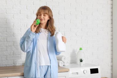 Evde çamaşır deterjanı kokusu alan genç bir kadın.