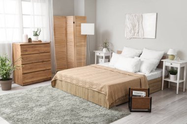 Rahat yatağı, dergileri ve ahşap mobilyaları olan şık bir yatak odası.