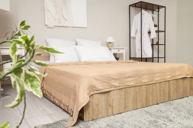 Rahat yatağı, elbise askılığı ve ahşap mobilyaları olan şık bir yatak odası.