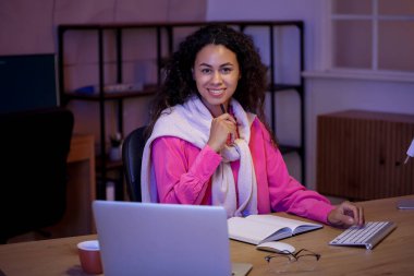 Genç Afro-Amerikalı soru cevap mühendisi geceleri dizüstü bilgisayarla ofiste çalışıyor.