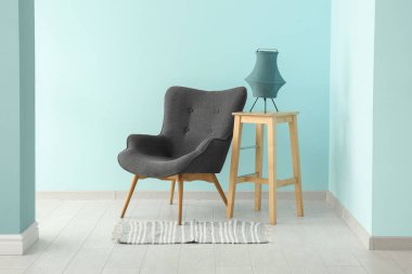 Mavi duvarın yanındaki siyah koltuk ve lamba.