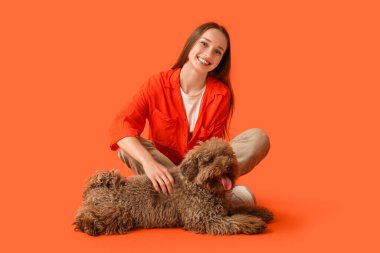 Kırmızı arka planda oturan sevimli kahverengi kaniş köpekli genç bir kadın.