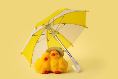 Sarı arka planda oyuncak piliçler olan mini şemsiye.