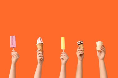 Turuncu arka planda farklı tatlı dondurmalı kadın elleri.