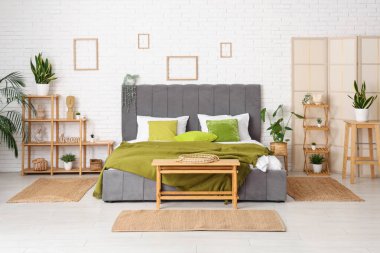 Rahat yatağı, raf ünitesi, bank ve bitkileri olan modern bir oda.