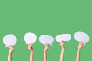 Yeşil arka planda konuşma baloncukları olan kadın eller