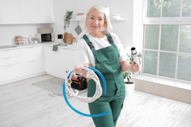 Mutfakta boruları olan olgun kadın tesisatçı.