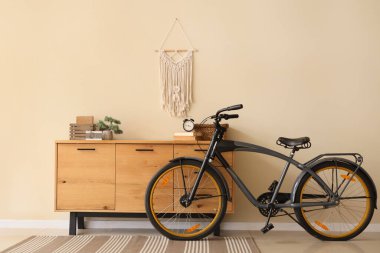 Çekmeceler ve bisiklet, odada bej duvarın yanında.