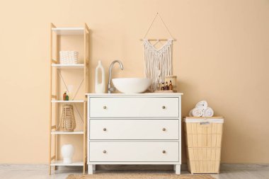 Çekmeceler, lavabo, raf ünitesi ve havlularla dolu sepet.