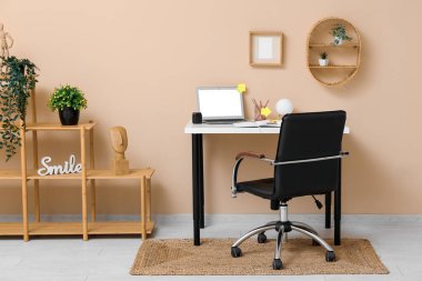 Masası, modern dizüstü bilgisayarı ve raf ünitesi olan hafif bir ofis.