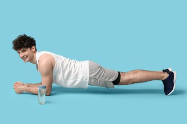 Mavi arka planda su şişesi olan sporcu.