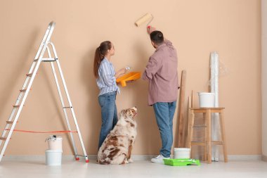 Yeni evlerinde duvarları boyayan sevimli köpekleri olan genç bir çift.