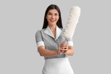 Işık arka planında pp-toz bezi olan genç oda hizmetçisi.