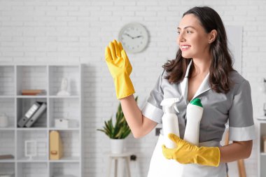 Ofisinde deterjan şişeleri olan genç oda hizmetçisi.