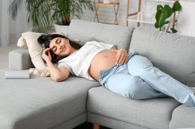 Güzel hamile kadın evde kanepeye yatan